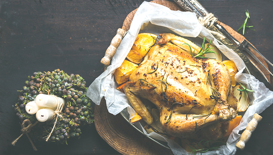 Close-up of roasted chicken with oganges, bulgur and rosemary